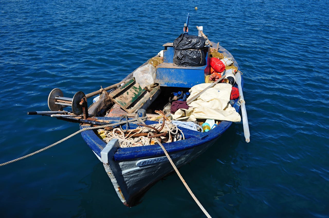 A fishing boat with gear anchored on calm blue ocean waters, showcasing a peaceful maritime scene.